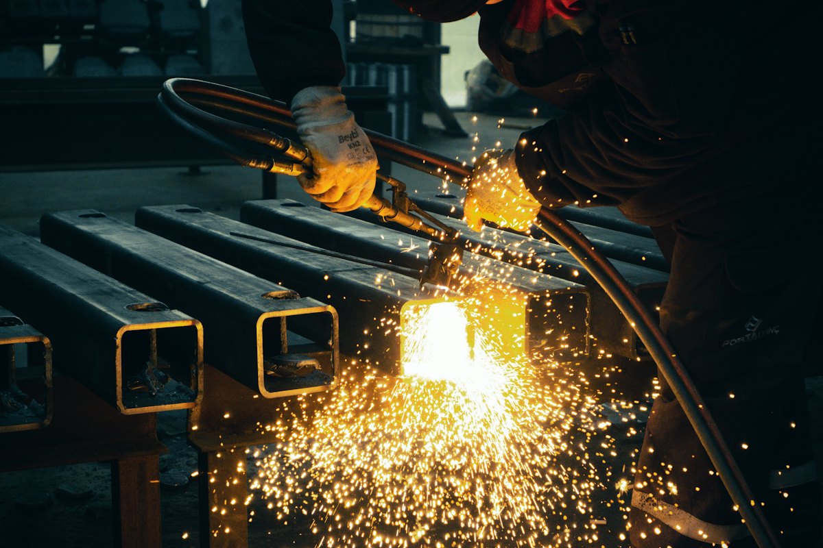 Torch cutting steel square tubing in a fabrication shop, sparks flying